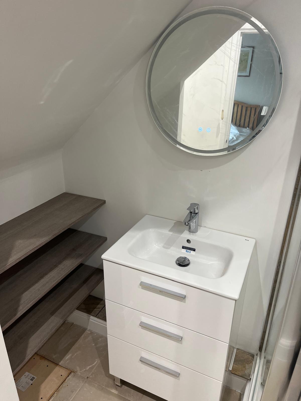 White vanity unit and LED mirror fitted under the eaves with oak shelving